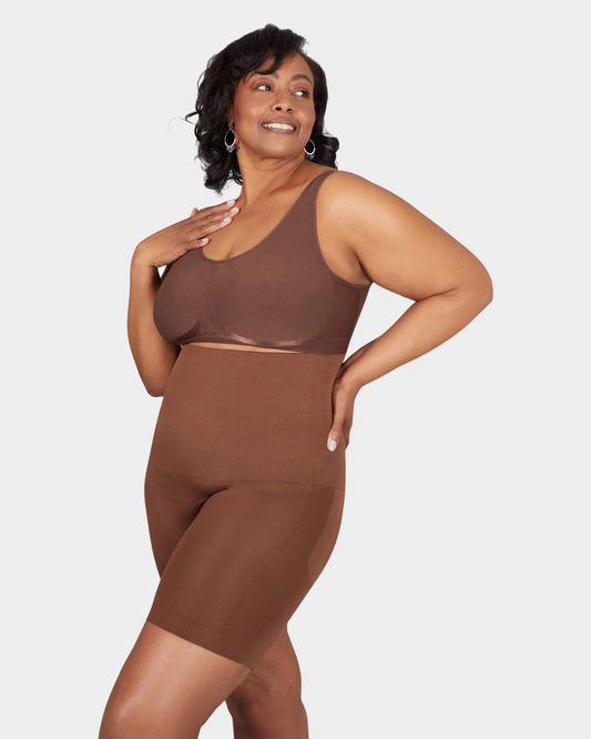 Woman wearing a brown shapewear outfit on a light gray background