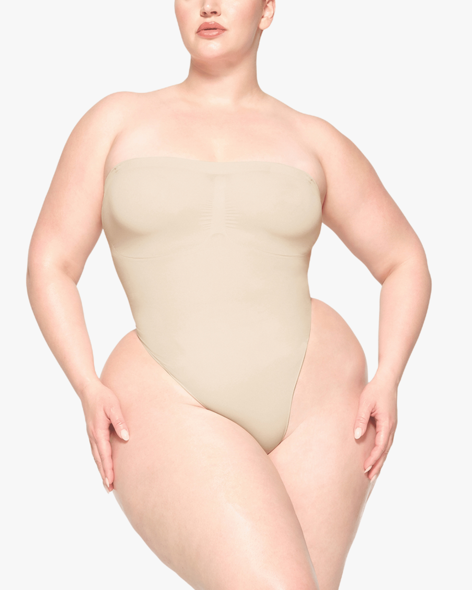 Woman wearing a beige strapless bodysuit on a white background