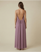 Woman wearing a long, light purple dress with thin straps on a beige background