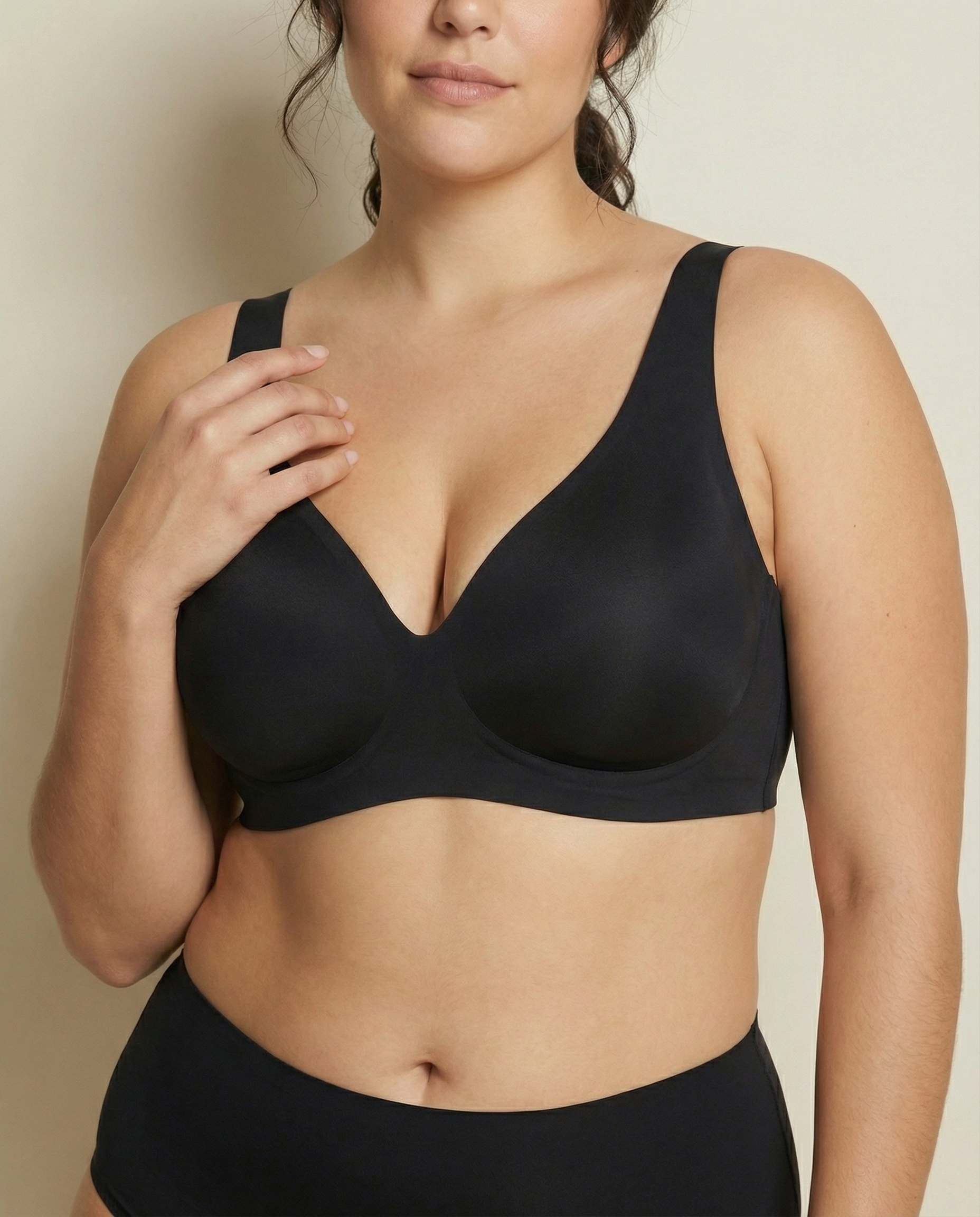 Woman wearing a black bra and underwear set against a neutral background