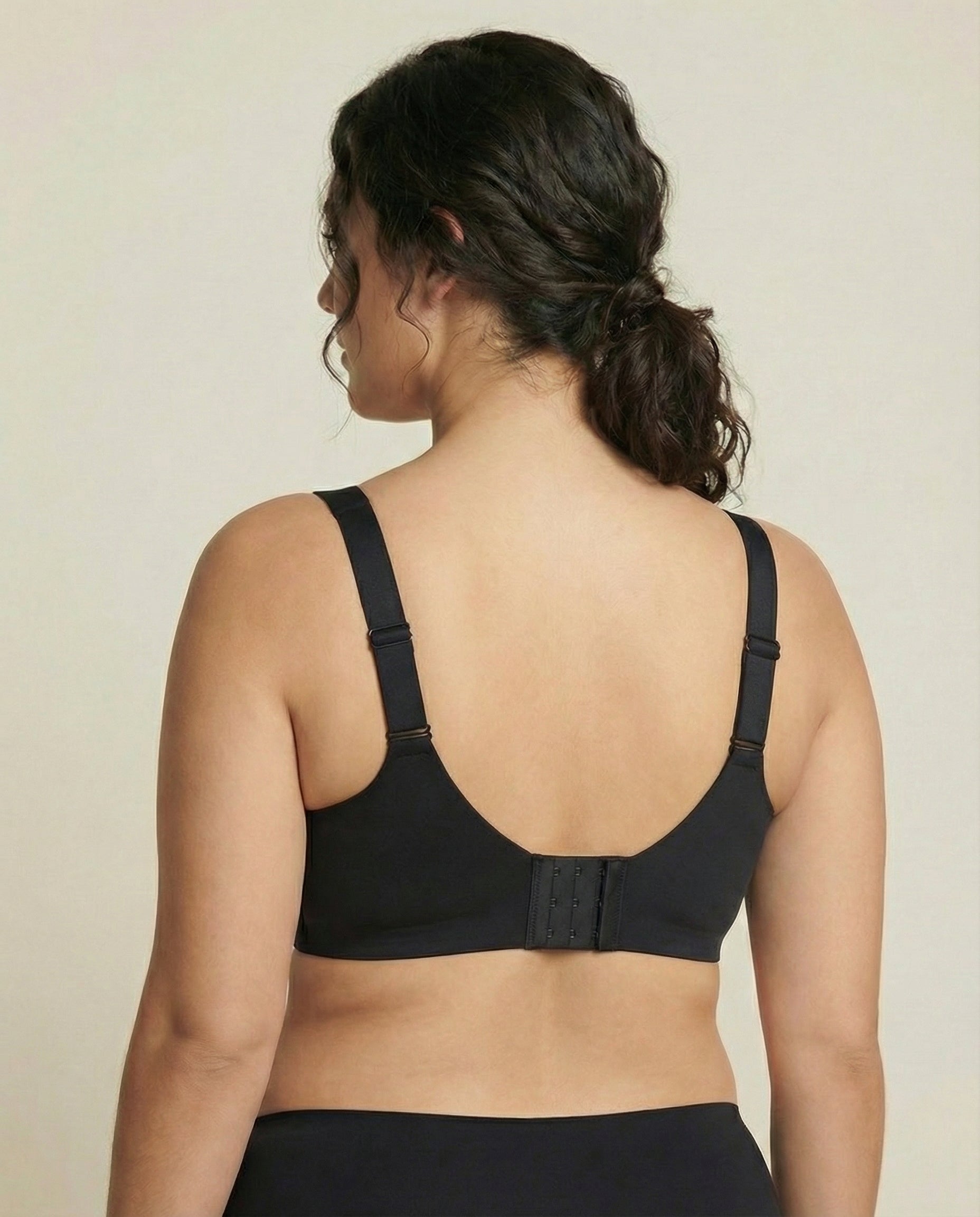 Person wearing a black bra against a beige background