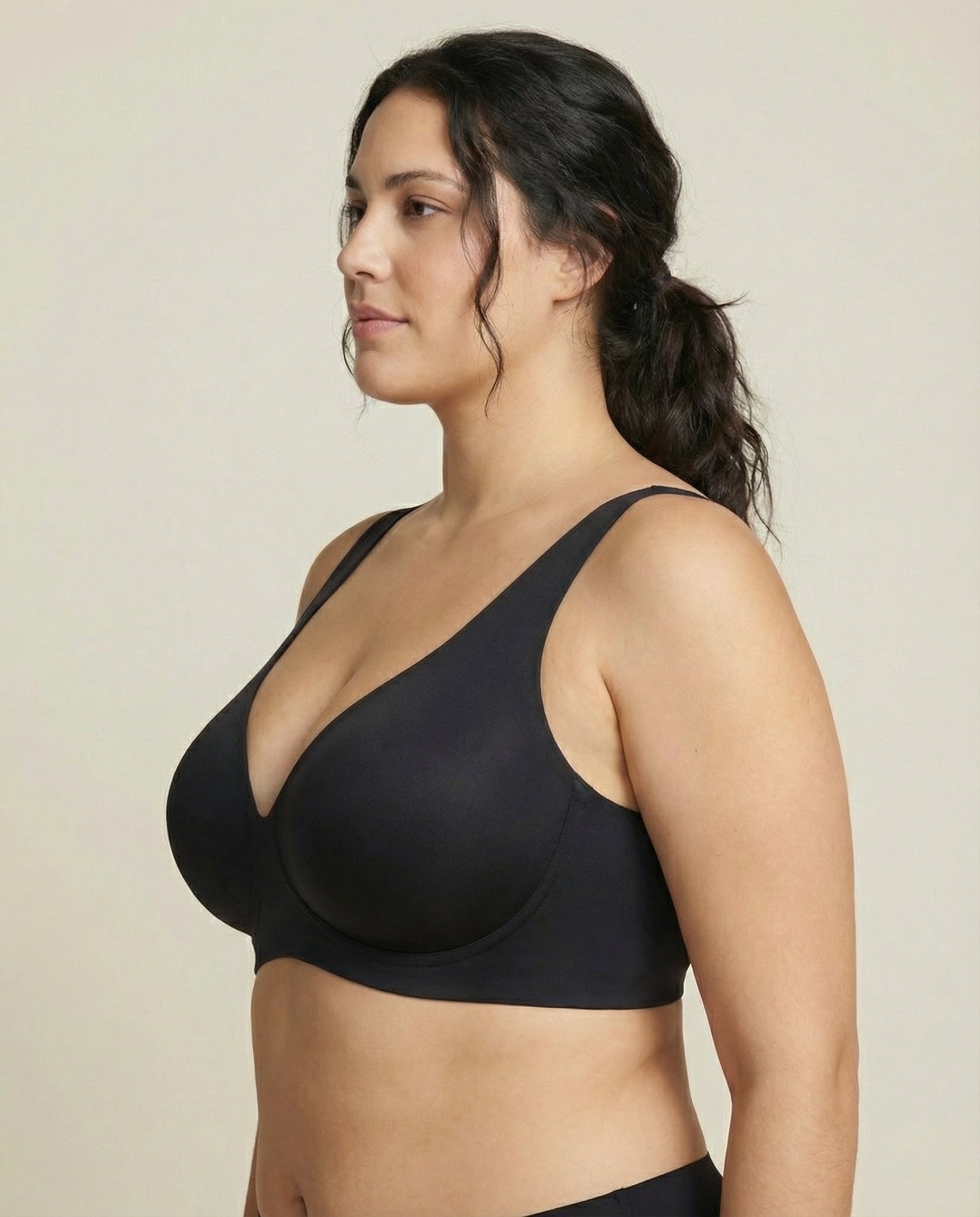 Woman wearing a black bra against a beige background