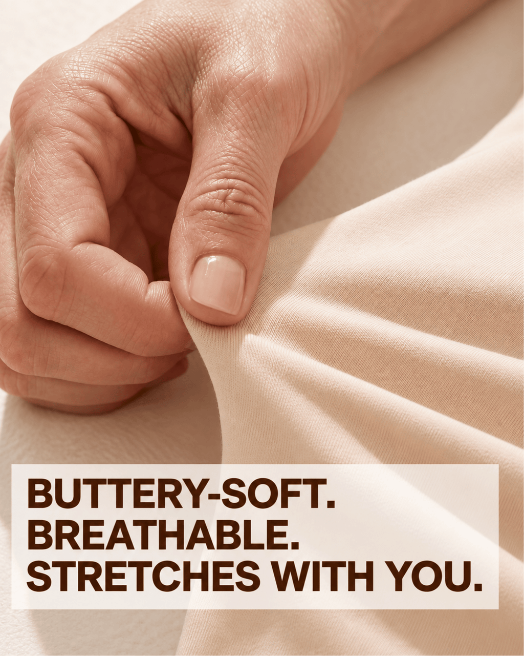A close-up of a hand stretching a soft beige fabric, with text overlay that reads: 'BUTTERY-SOFT. BREATHABLE.