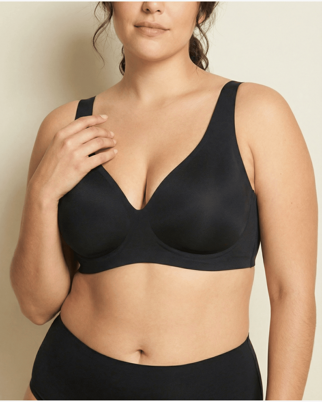 Woman wearing a black bra against a neutral background
