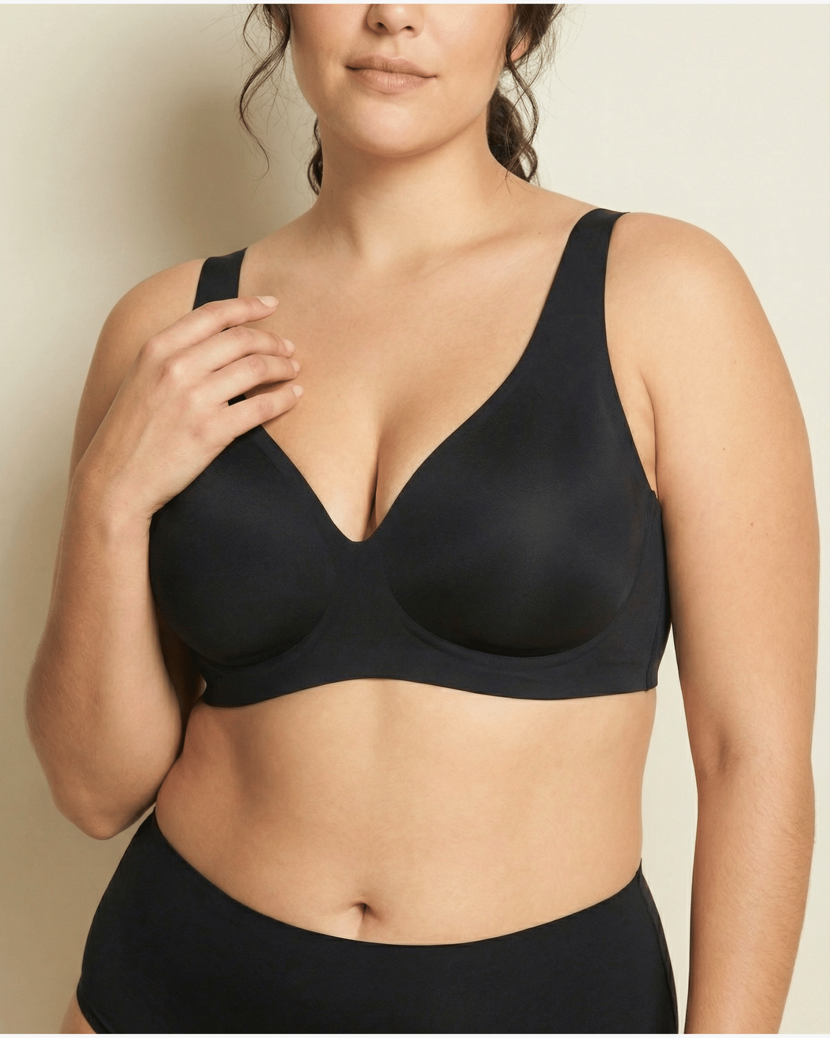 Woman wearing a black bra against a neutral background
