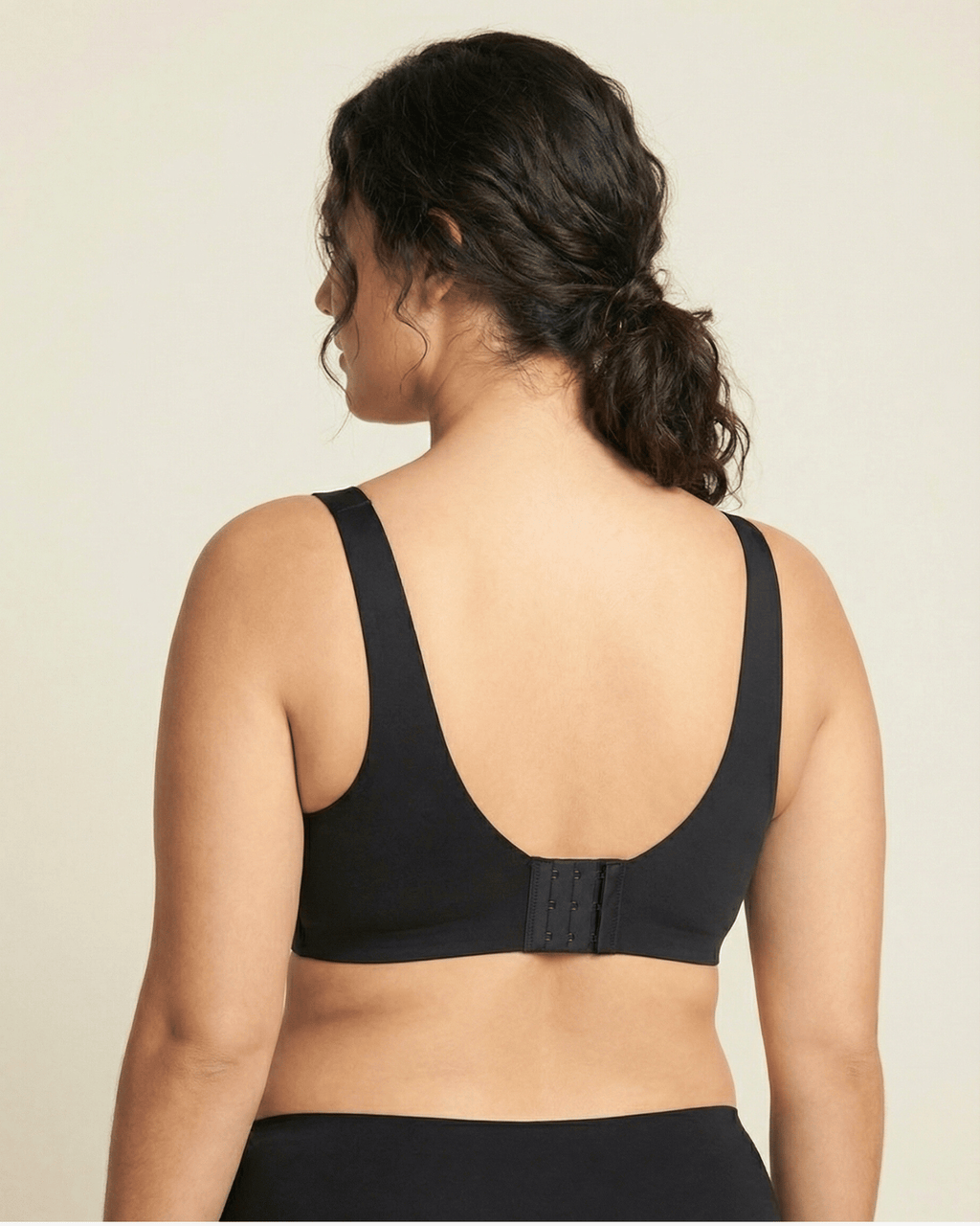 Black sports bra worn by a person on a beige background
