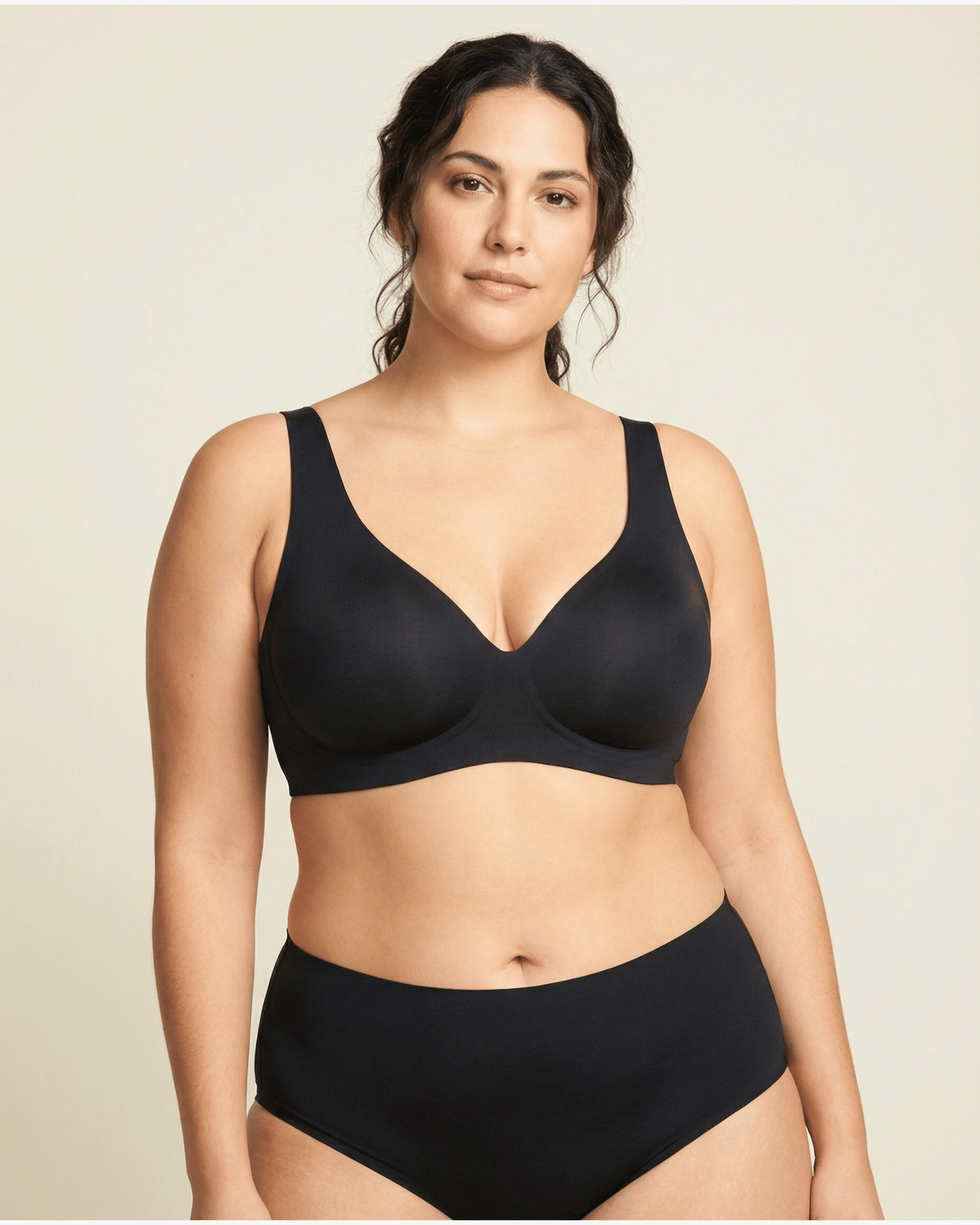 Woman wearing a black bra and panties set on a beige background