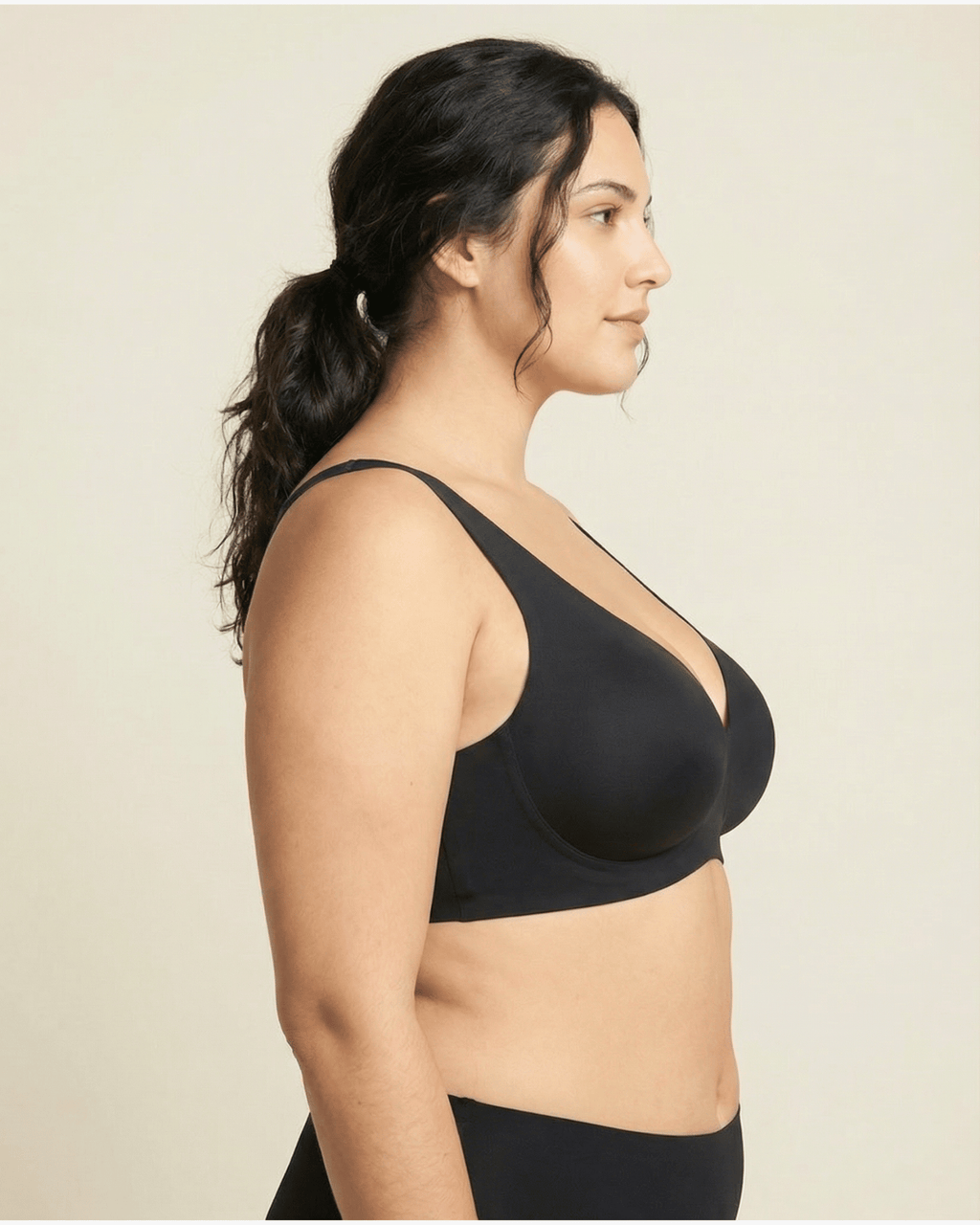 Woman wearing a black bra against a beige background