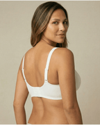 Woman wearing a white bra against a beige background