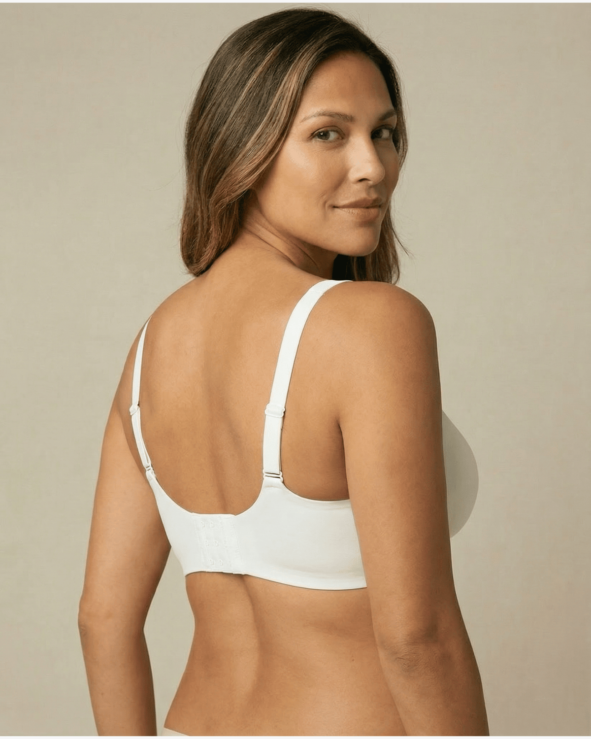 Woman wearing a white bra against a beige background