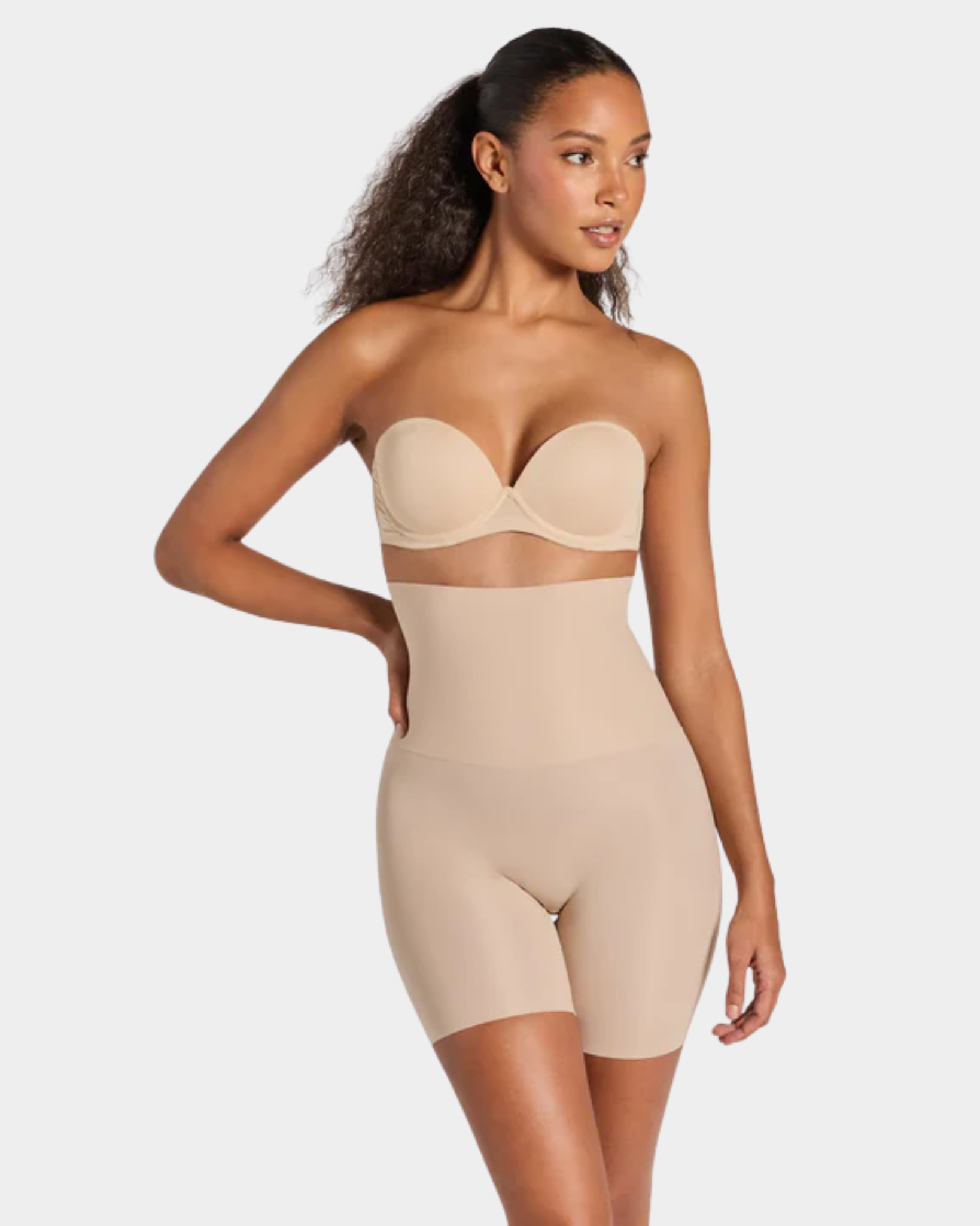 Woman wearing a beige shapewear bodysuit on a white background