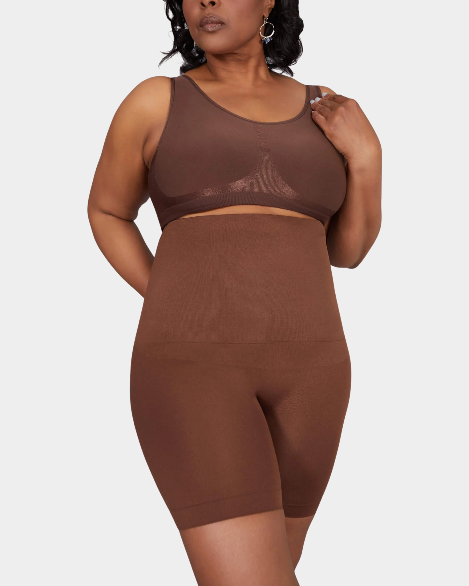 Person wearing a brown sports bra and shorts set on a white background