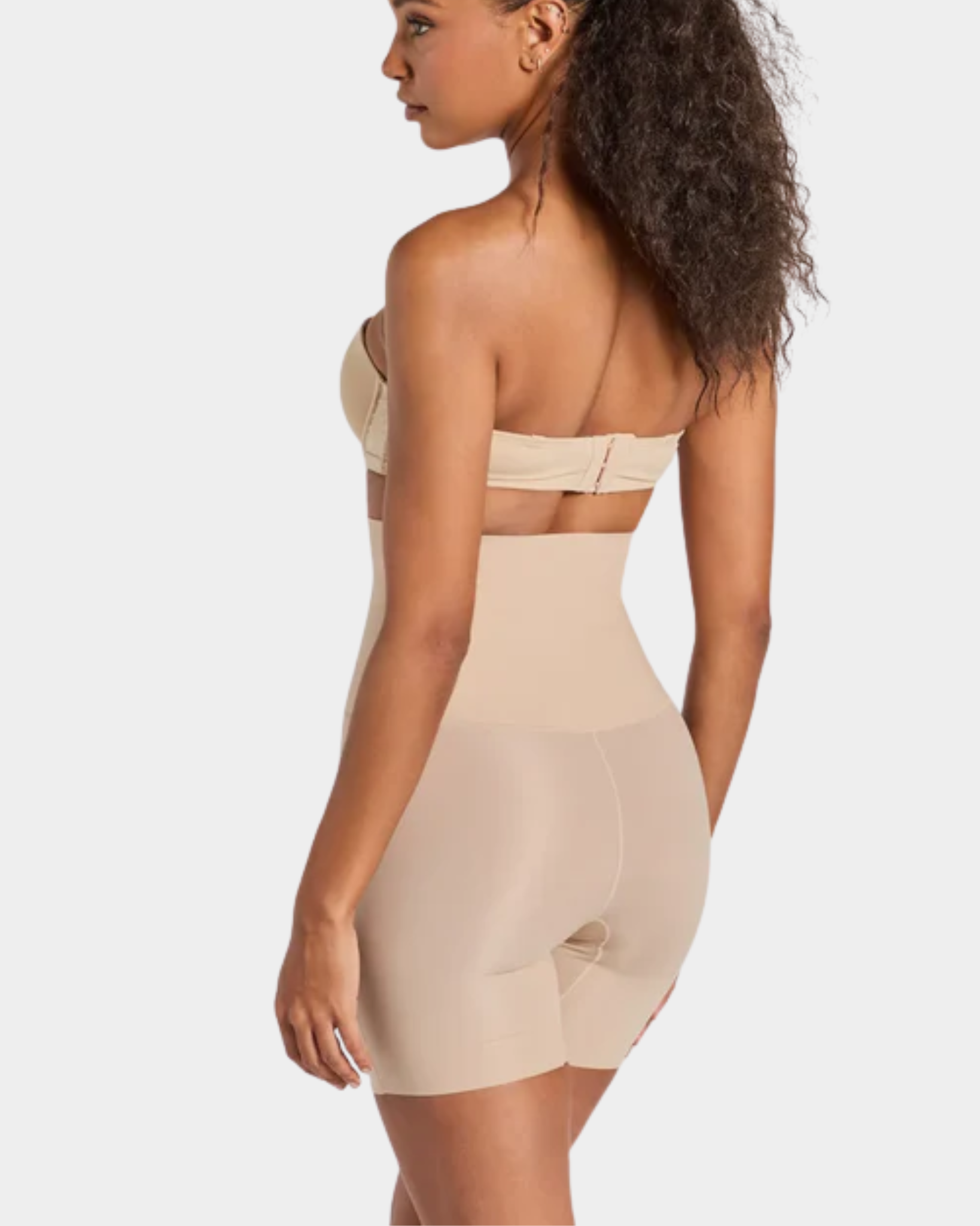 Woman wearing a beige strapless top and shapewear on a white background