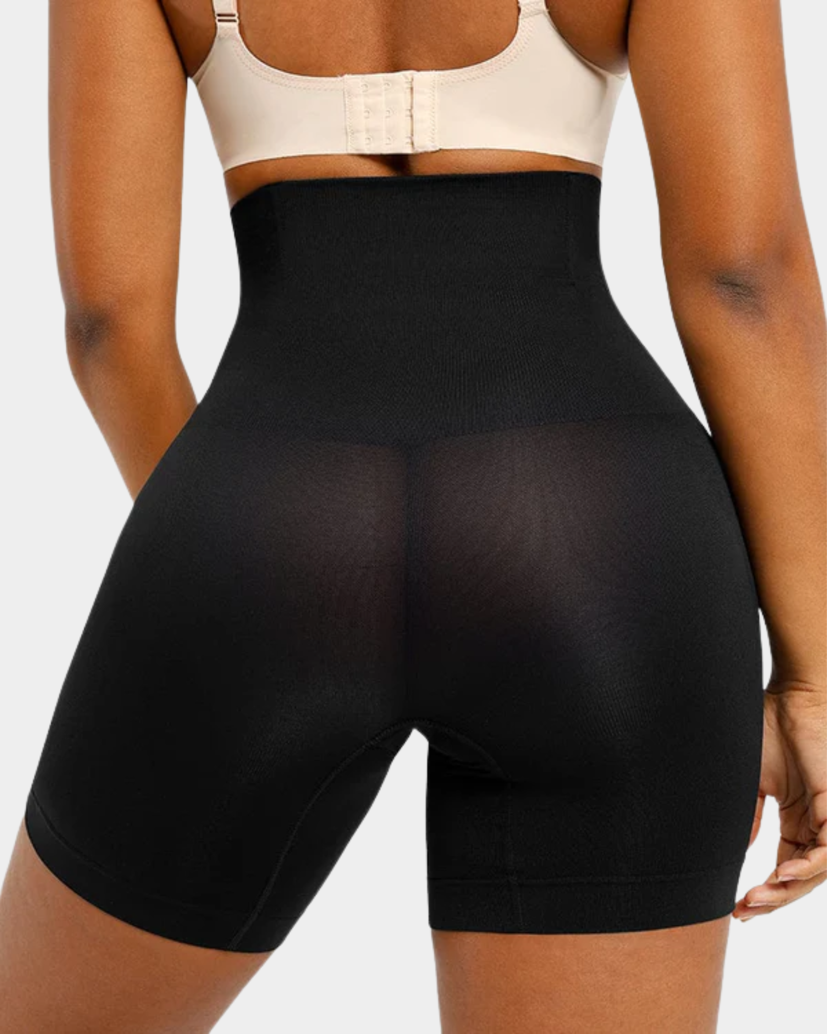 Person wearing black high-waisted shapewear shorts on a plain background