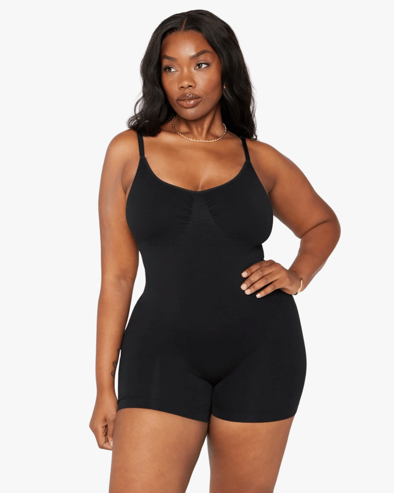 Woman wearing a black bodysuit against a white background