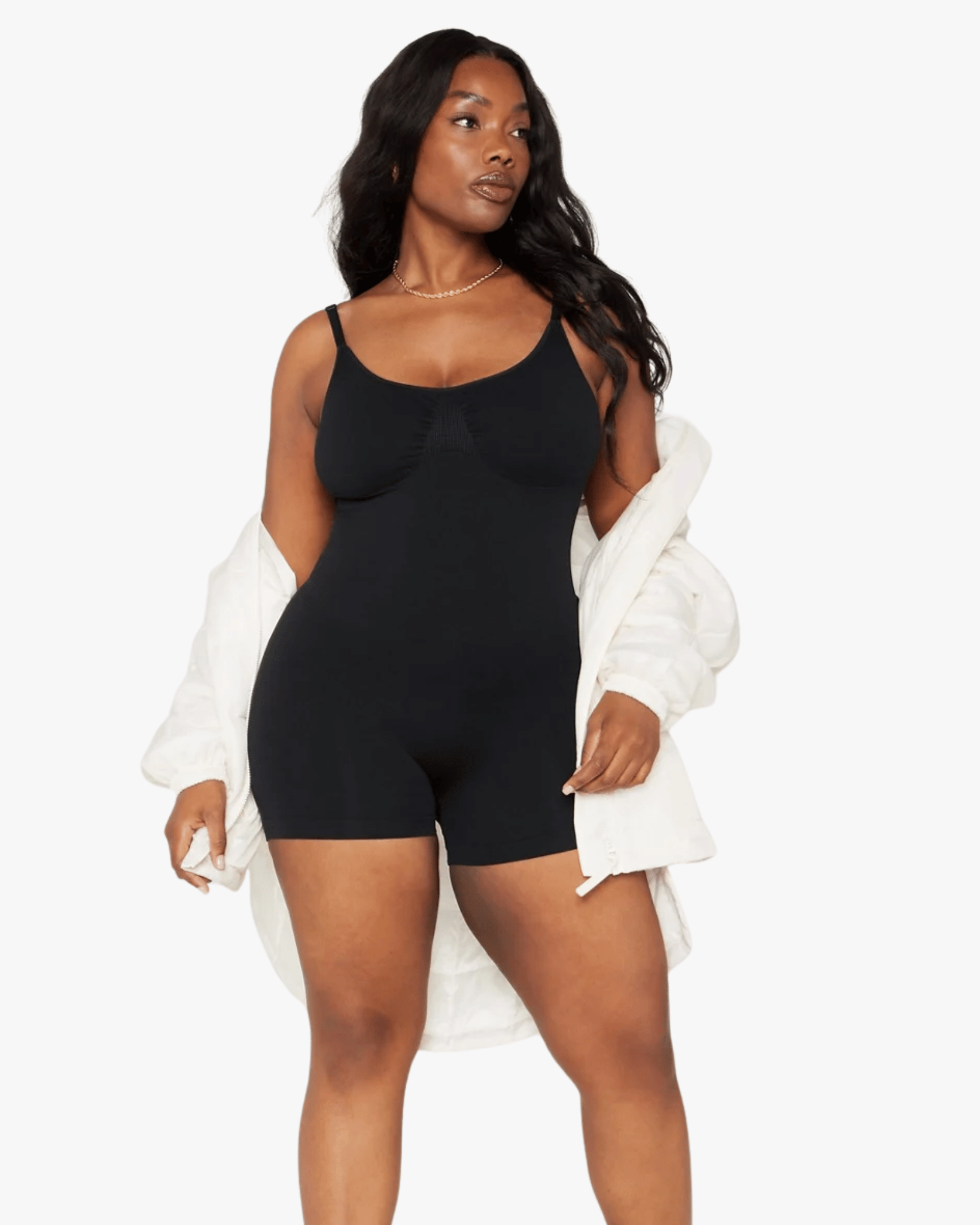 Woman wearing a black bodysuit with a white jacket on a white background