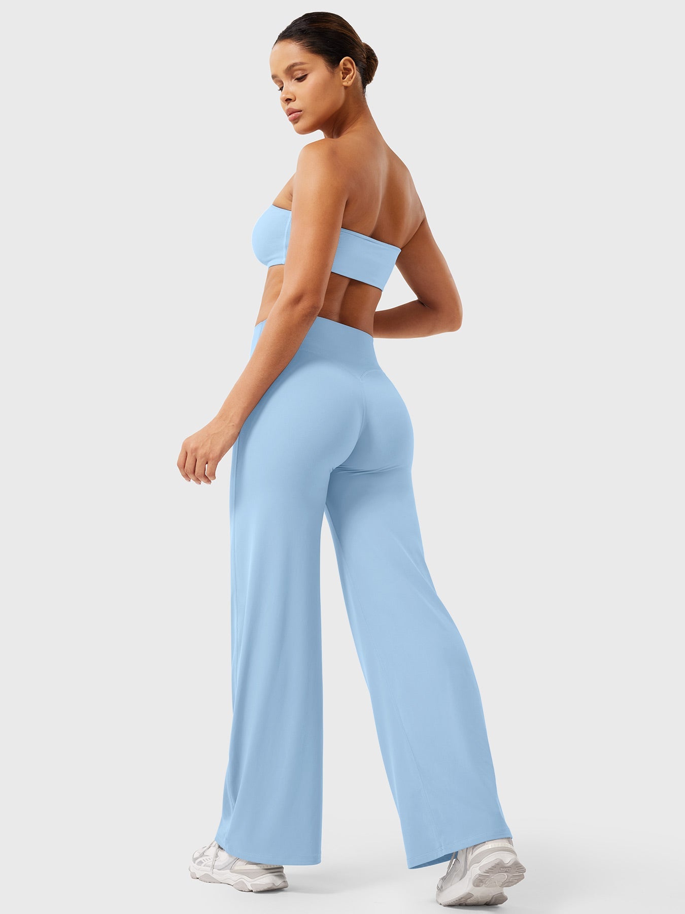 Woman wearing a light blue sports bra and leggings set on a white background